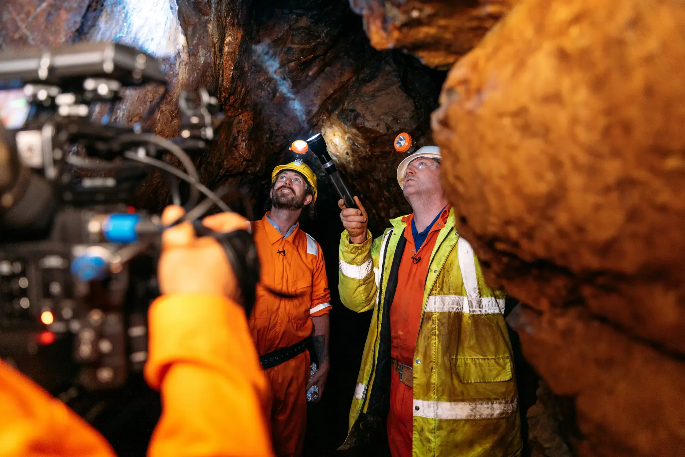 James Strawbridge and a Cornish Metals guide examining the rock face underground at South Crofty while PixelRain films