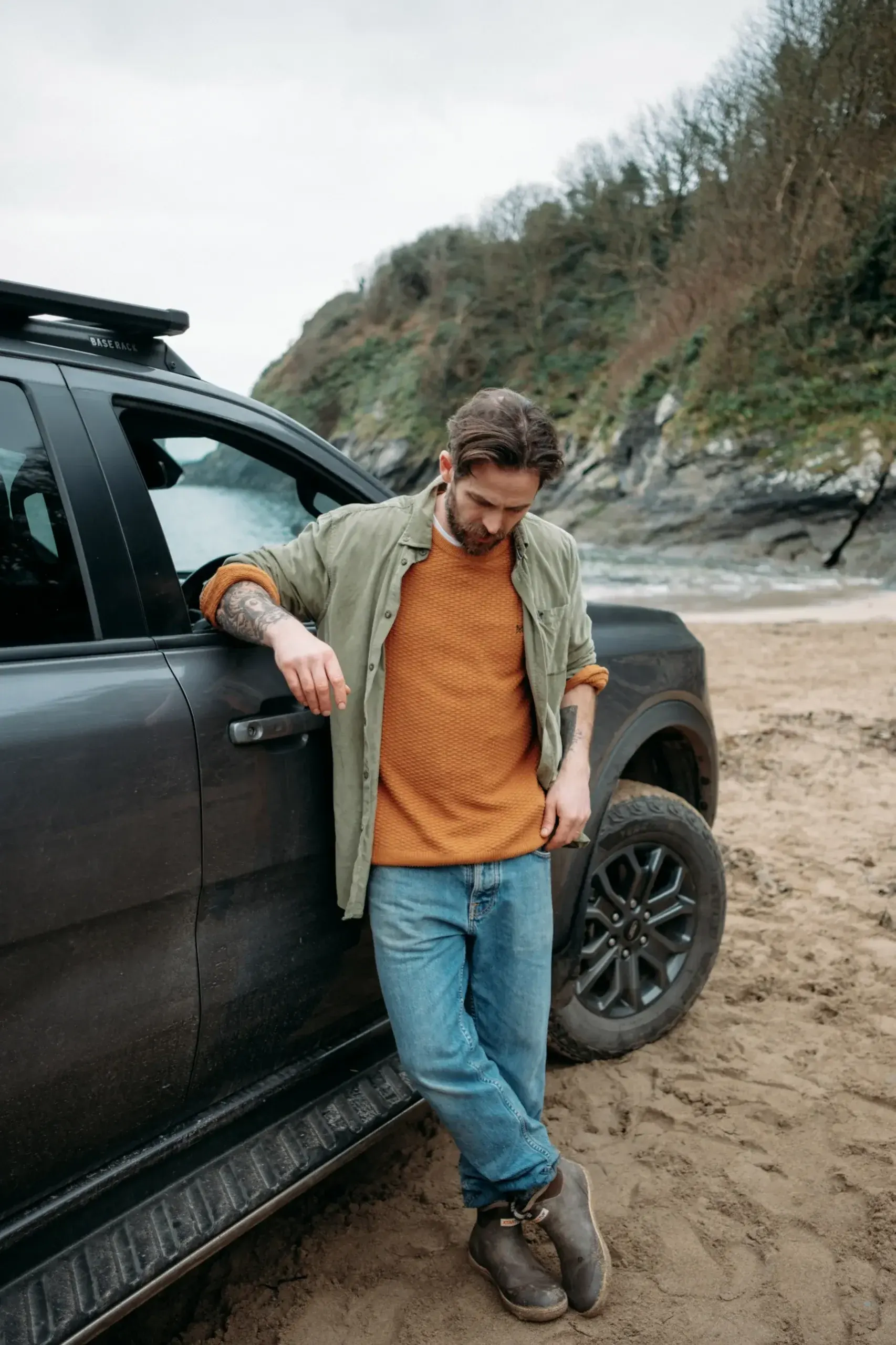 James Strawbridge standing beside a Ford Ranger during a vertical location shoot on a Cornish beach