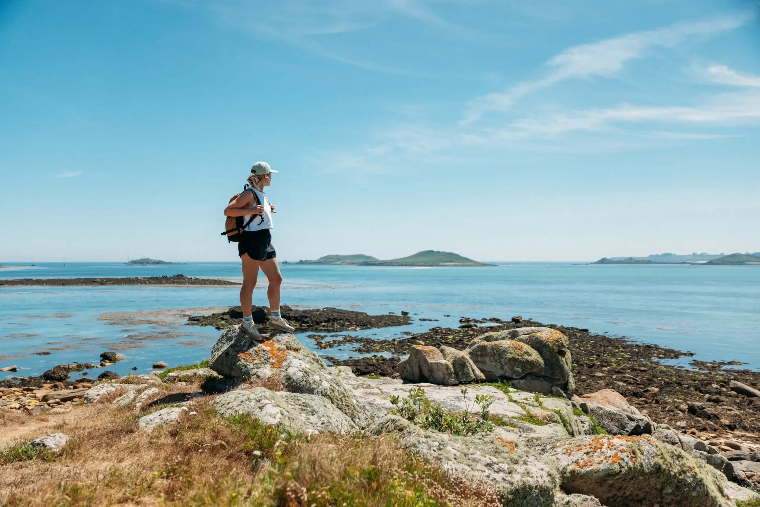 A walker standing on coastal rocks during a destination content production in the Isles of Scilly