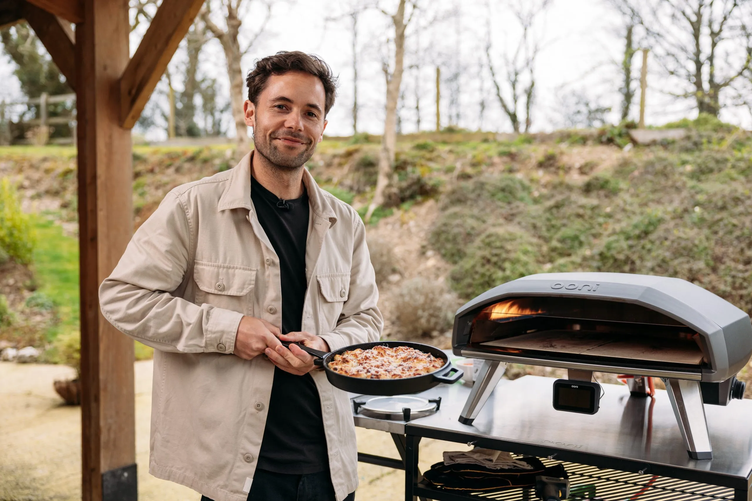 Grant Batty holding freshly baked garlic knots beside an Ooni oven