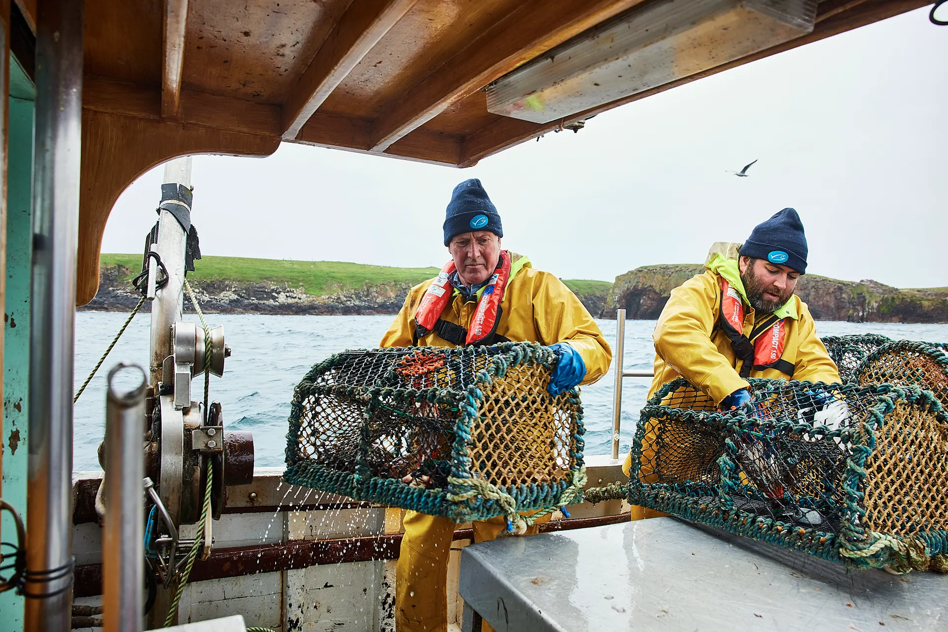 Two crab fishermen hauling pots aboard a fishing boat in Shetland, photographed by David Loftus during the All Hands On Deck campaign shoot