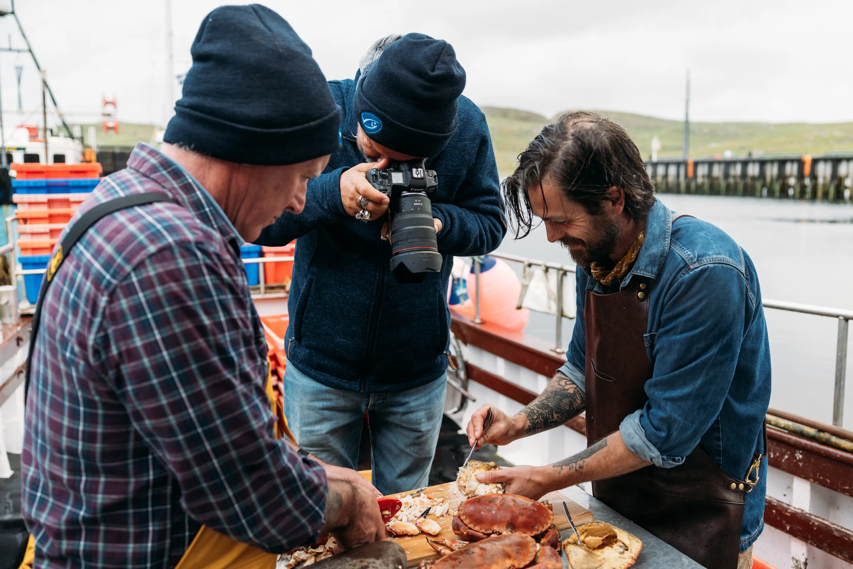 A crab fisherman, photographer David Loftus and James Strawbridge preparing and photographing crab for a digital series in Shetland