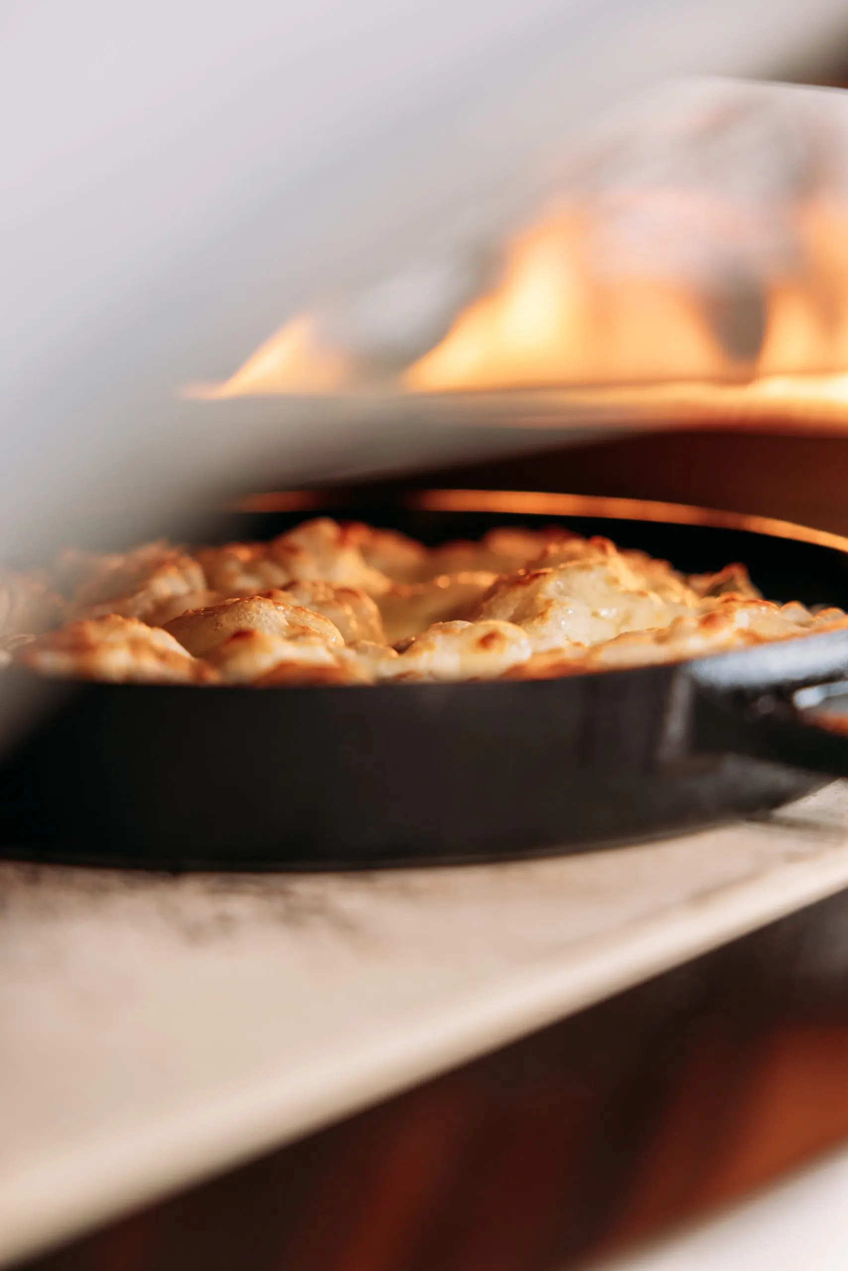 Garlic knots cooking in a cast iron pan inside the Ooni Koda 2 Pro pizza oven during a PixelRain recipe video shoot for Ooni UK